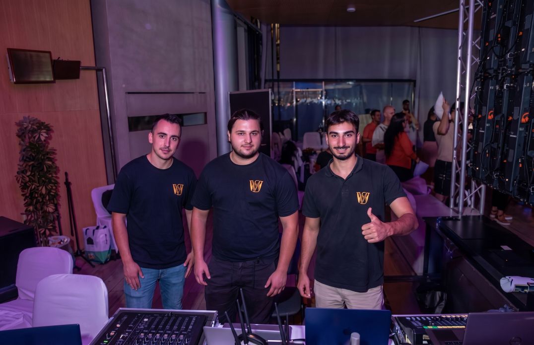 Equipo de técnicos audiovisuales de Vibescene detrás de la mesa de control de sonido e iluminación durante la producción de un evento en directo.